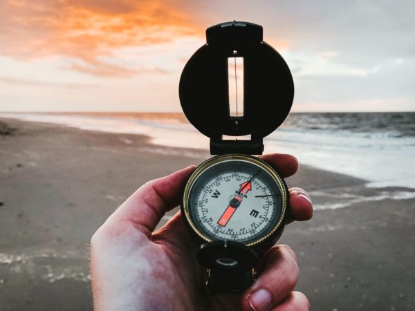 Man holding a compass looking for directions on a beach